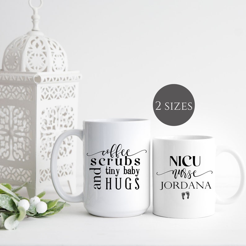 May include: Two white coffee mugs with black text. The mug on the left says "coffee scrubs and tiny baby hugs". The mug on the right says "NICU nurse JORDANA" with two small footprints below the text.