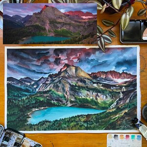 Puede incluir: Pintura acuarela de una cordillera con un lago en primer plano. El cielo es de un azul dram&aacute;tico con nubes oscuras y un toque de rosa en la distancia. Las monta&ntilde;as son una mezcla de verde y marr&oacute;n, con algunos picos rojos. El lago es de un azul turquesa brillante.