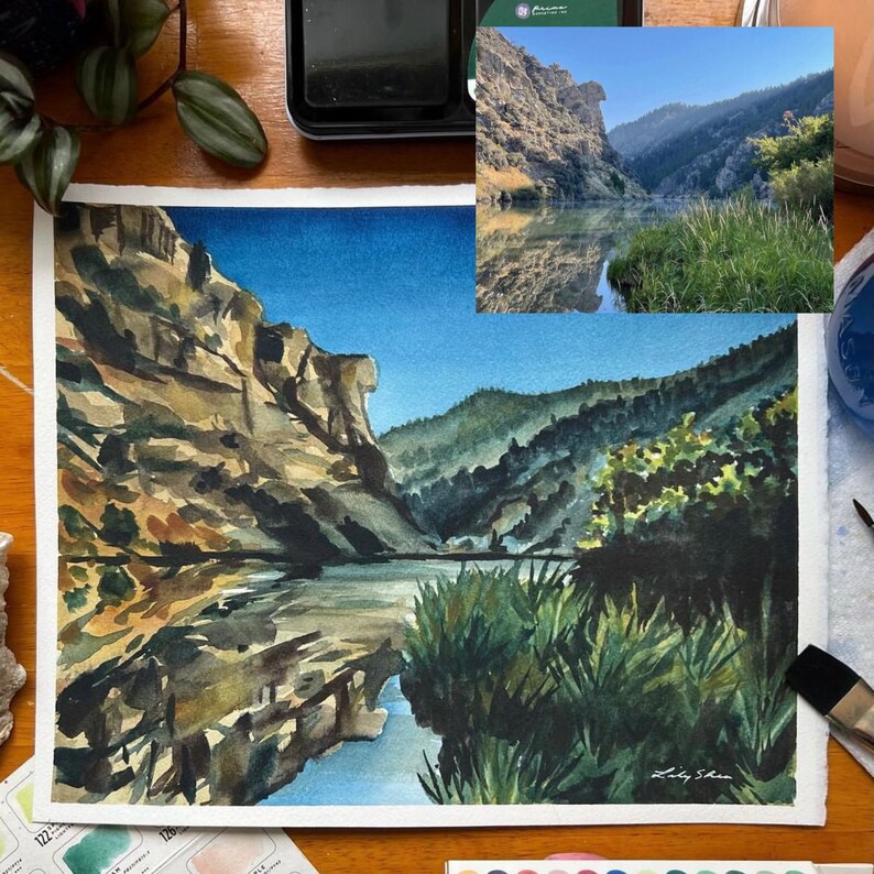 Puede incluir: Pintura acuarela de un ca&ntilde;&oacute;n con un r&iacute;o que lo atraviesa. Las paredes del ca&ntilde;&oacute;n son una mezcla de marr&oacute;n, beige y verde. El r&iacute;o es de color azul claro. La pintura est&aacute; firmada "Lily Shen".