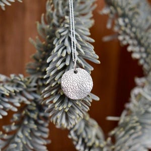 May include: A white ceramic mug with a black handle and the text "But First, Coffee" in a bold, black font. The mug is set against a neutral background, highlighting its simple design.