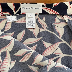 May include: Close-up of a navy blue fabric with a cream and red leaf pattern. The tag reads "Rena Rowan" and "10". The fabric is made of 100% rayon and is dry clean only.