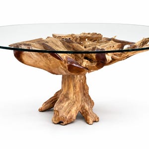 May include: A round coffee table featuring a clear glass top supported by a natural light brown tree root base. The base consists of interconnected, organic wooden segments that form a sturdy pedestal, showcasing the raw texture of wood.
