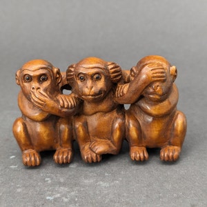 May include: Three wooden monkeys carved in a traditional style, each covering a different sense. One monkey covers its eyes, another its ears, and the third its mouth. The monkeys are brown and have realistic features.