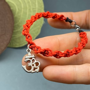 Hand braided bracelet with silver charm: sterling silver charm of a character, buddha teaching, red cord braided bracelet