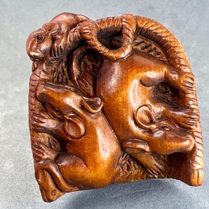 Puede incluir: Una escultura de madera tallada a mano de tres ratas, una de las cuales está enroscada en la parte superior de las otras dos. La escultura está hecha de madera marrón oscura y tiene un diseño detallado y realista.