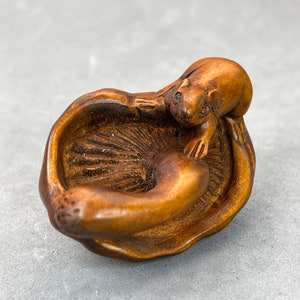 May include: A small, intricately carved wooden sculpture of a squirrel curled up inside a hollowed-out mushroom.