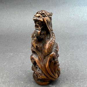 Peut inclure: Une sculpture en bois détaillée d'un dragon avec des détails complexes et une finition brun foncé.