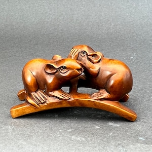 Puede incluir: Una escultura de madera tallada a mano de dos ratones en una rama. Los ratones son marrones y tienen rasgos detallados. La escultura es un netsuke japonés tradicional.