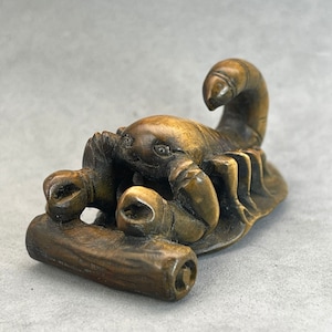 May include: A hand-carved wooden sculpture of a scorpion, with intricate details and a realistic appearance. The scorpion is curled up on a log, with its tail raised and its claws extended.