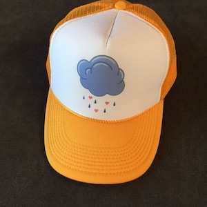 Puede incluir: Una gorra de camionero amarilla y blanca con un gráfico de una nube azul y gotas de lluvia rojas.