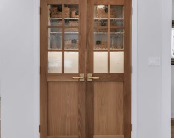 May include: Double French doors with frosted glass panels and brass hardware. The doors are made of wood and have a natural finish. The doors are open to reveal a pantry with shelves and baskets. The text "Northern Edge Woodshop Co." is visible at the bottom of the image.