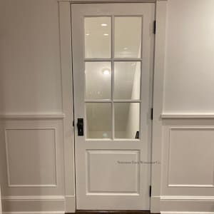 May include: White door with a glass pane and a single black door handle. The door has a white frame and is labeled "Northern Edge Woodshop Co."