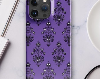 May include: Purple phone case with a repeating pattern of a haunted mansion with a ghostly face. The case is designed for an iPhone.