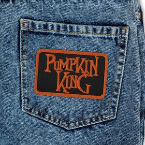 May include: A pair of blue denim jeans with a black and orange patch on the back pocket that says "Pumpkin King".