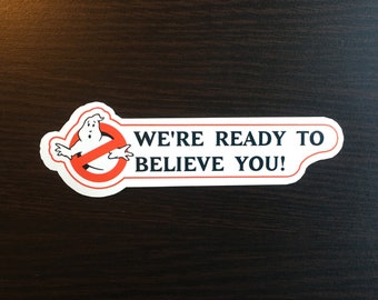 May include: White sticker with a red circle and a ghost inside. The text "We're ready to believe you!" is written on the sticker.