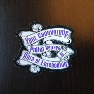 May include: A black and white sticker with a purple text overlay. The text reads "Your Cadaverous Pallor Betrays an Aura of Foreboding".