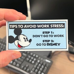 May include: A blue and white card with Mickey Mouse's head on it. The card says "Tips to Avoid Work Stress: Step 1: Don't Go to Work. Step 2: Go to Disney."