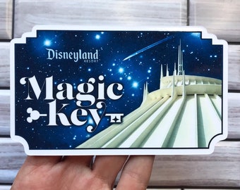 May include: A blue and white sticker with a white building against a dark blue starry sky. The text "Disneyland Resort" and "Magic Key" are in white letters.