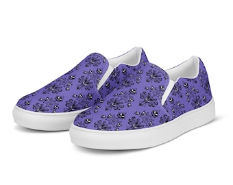May include: A pair of purple slip-on shoes with a black and white pattern. The pattern features a repeating design of a haunted house with a ghost.