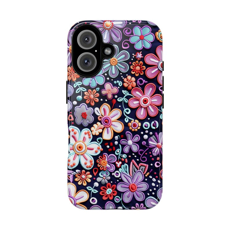 Op de afbeelding: Een telefoonhoesje met een bloemenpatroon. De hoes is versierd met verhoogde bloemen in verschillende kleuren, waaronder roze, paars, oranje en blauw, tegen een donkere achtergrond. Het heeft een glanzende afwerking en een camera-opening.