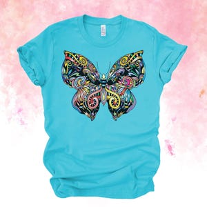A turquoise t-shirt with a colorful, intricate butterfly design printed on it.