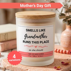 K&ouml;nnte beinhalten: Eine Kerze aus mattiertem Glas mit einem Holzdeckel. Auf dem Etikett steht "Smells Like Grandmother Runs This Place". Die Kerze ist 198 g und aus Sojawachs. Das Bild enth&auml;lt auch den Text "Mother's Day Gift" und "4 variations."