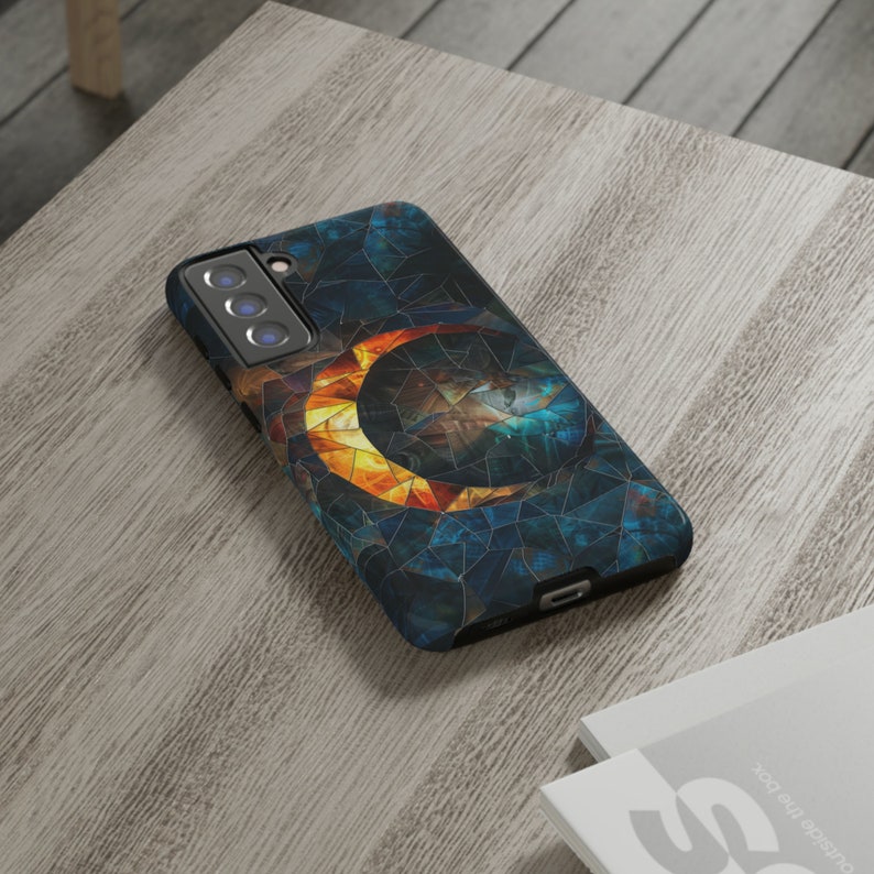 May include: A black phone case with a colorful abstract design featuring a crescent moon and a mosaic pattern.
