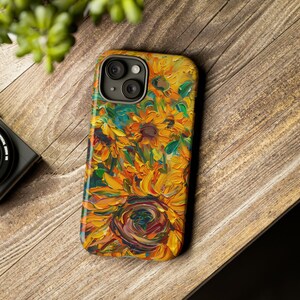 May include: A phone case featuring a colourful painting of sunflowers. The case has a camera cutout and a black border.