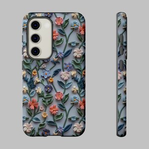 Op de afbeelding: Een telefoonhoesje met een bloemenpatroon. Het hoesje is gemaakt van hard plastic en heeft een reli&euml;f bloemenpatroon. De bloemen zijn in tinten roze, blauw en groen. Het hoesje is ontworpen om te passen op een smartphone met een camerabult.