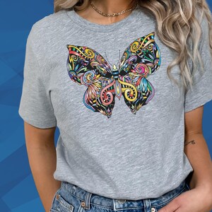 A woman wearing a gray t-shirt with a colorful butterfly design on it.