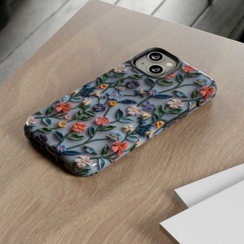 Op de afbeelding: Een blauwe telefoonhoes met een bloemenpatroon. De bloemen zijn reli&euml;f en hebben een 3D-effect. De hoes is gemaakt van een zacht, flexibel materiaal.