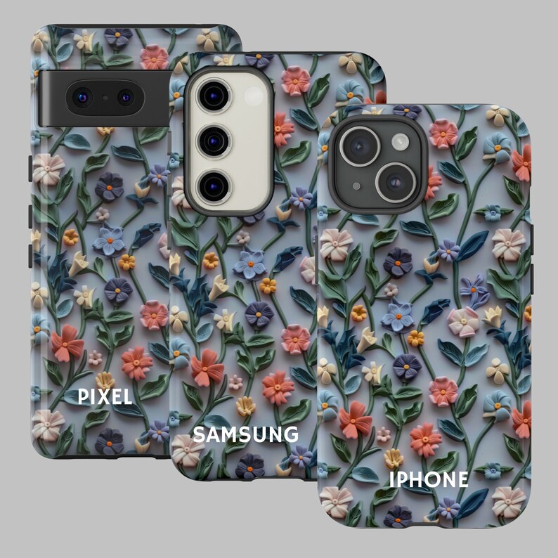 Op de afbeelding: Drie telefoonhoesjes met een bloemenpatroon. De hoesjes zijn voor Pixel-, Samsung- en iPhone-telefoons. Het ontwerp heeft een lichtblauwe achtergrond met 3D-bloemen in tinten roze, perzik en wit.