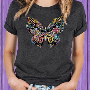 A woman wearing a gray t-shirt with a colorful butterfly design on it.