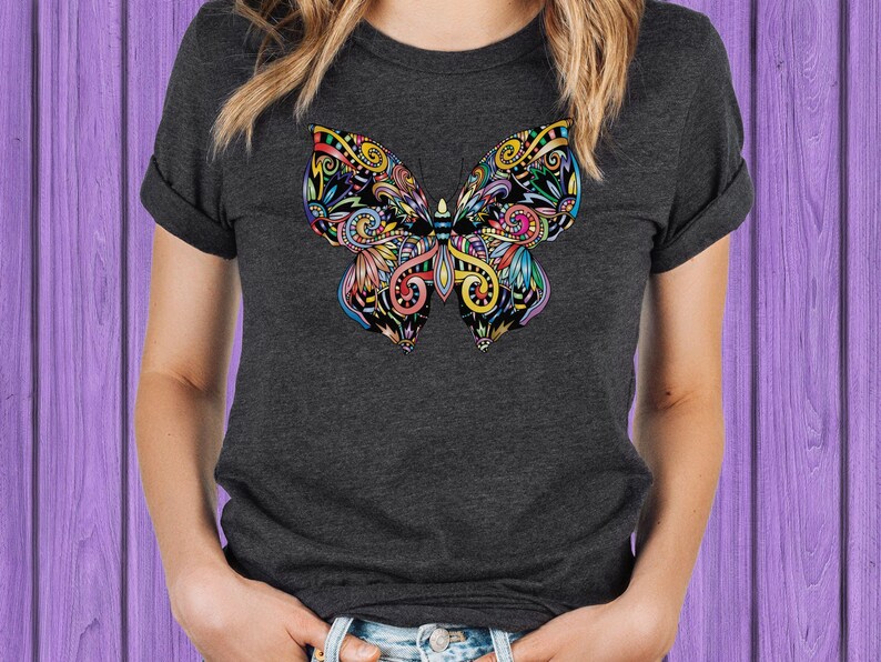 A woman wearing a gray t-shirt with a colorful butterfly design on it.