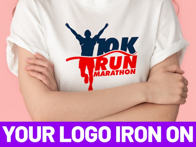 K&ouml;nnte beinhalten: Wei&szlig;es T-Shirt mit einem aufb&uuml;gelbaren Design in Blau und Rot, das einen L&auml;ufer zeigt, der die Ziellinie &uuml;berquert. Das Design enth&auml;lt den Text "10K RUN MARATHON".
