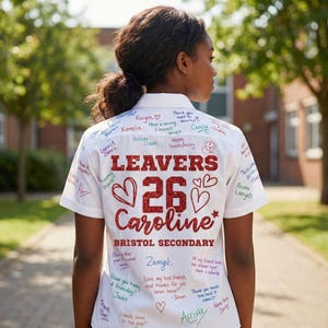 Peut inclure: Une chemise blanche &agrave; manches courtes avec des messages et des signatures manuscrites. La chemise pr&eacute;sente les mots "LEAVERS 26 Caroline" en paillettes rouges, avec des c&oelig;urs et le texte "Bristol Secondary".