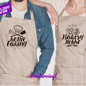 K&ouml;nnte beinhalten: Zwei braune Leinensch&uuml;rzen mit B&uuml;gelmotiven. Eine Sch&uuml;rze zeigt einen Kochhut, einen Schneebesen und einen Spatel mit dem Text "home baking". Die andere Sch&uuml;rze zeigt ein Design mit Br&ouml;tchen mit dem Text "Bakery House".
