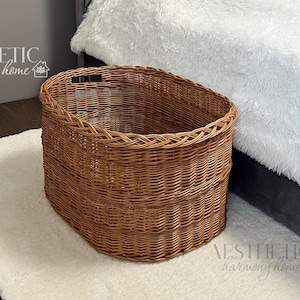 May include: A brown wicker basket with a gray headboard and white bedding in the background. The basket is oval shaped and has a woven pattern. The text "AESTHETIC harmony home" is visible in the bottom right corner of the image.