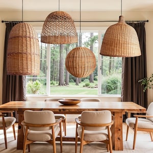 Puede incluir: Comedor con una mesa de madera y seis sillas beige. Cuatro lámparas colgantes de ratán tejido cuelgan sobre la mesa. La habitación tiene una paleta de colores neutros con cortinas marrones y vistas a un bosque a través de una ventana.