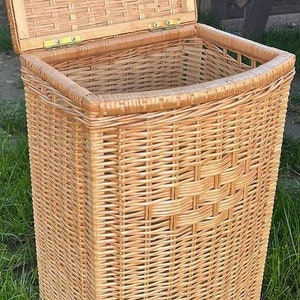 May include: A natural woven wicker storage basket with a hinged lid. The basket is light brown and has a rectangular shape with rounded edges.