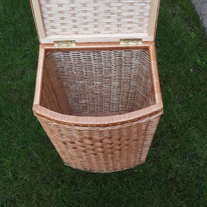 May include: A woven wicker basket with a hinged lid. The basket is light brown and has a natural woven pattern. The lid is open and the inside of the basket is visible.