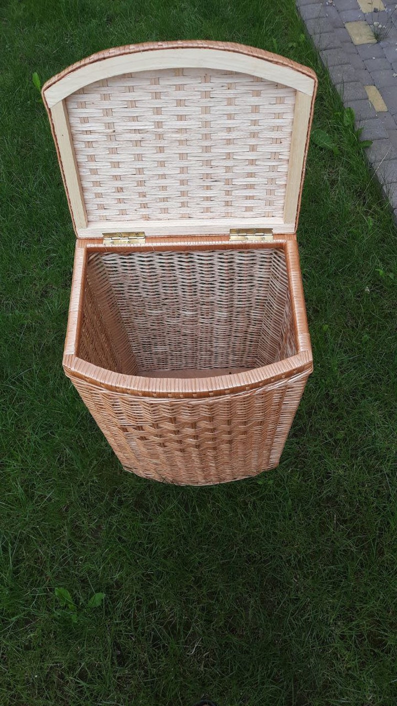 May include: A woven wicker basket with a hinged lid. The basket is light brown and has a natural woven pattern. The lid is open and the inside of the basket is visible.