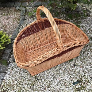 Op de afbeelding: Een geweven rieten mand met een bruin en natuurlijk ontwerp. De mand heeft een enkele handgreep en is ideaal voor het dragen van voorwerpen.