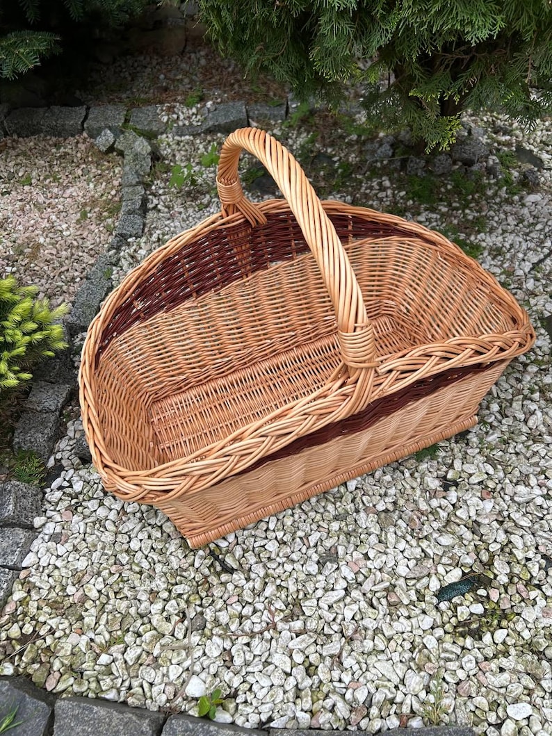 Op de afbeelding: Een geweven rieten mand met een bruin en natuurlijk ontwerp. De mand heeft een enkele handgreep en is ideaal voor het dragen van voorwerpen.