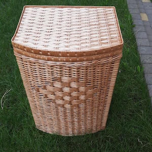 May include: A woven wicker laundry basket with a lid. The basket is light brown and has a rectangular shape.