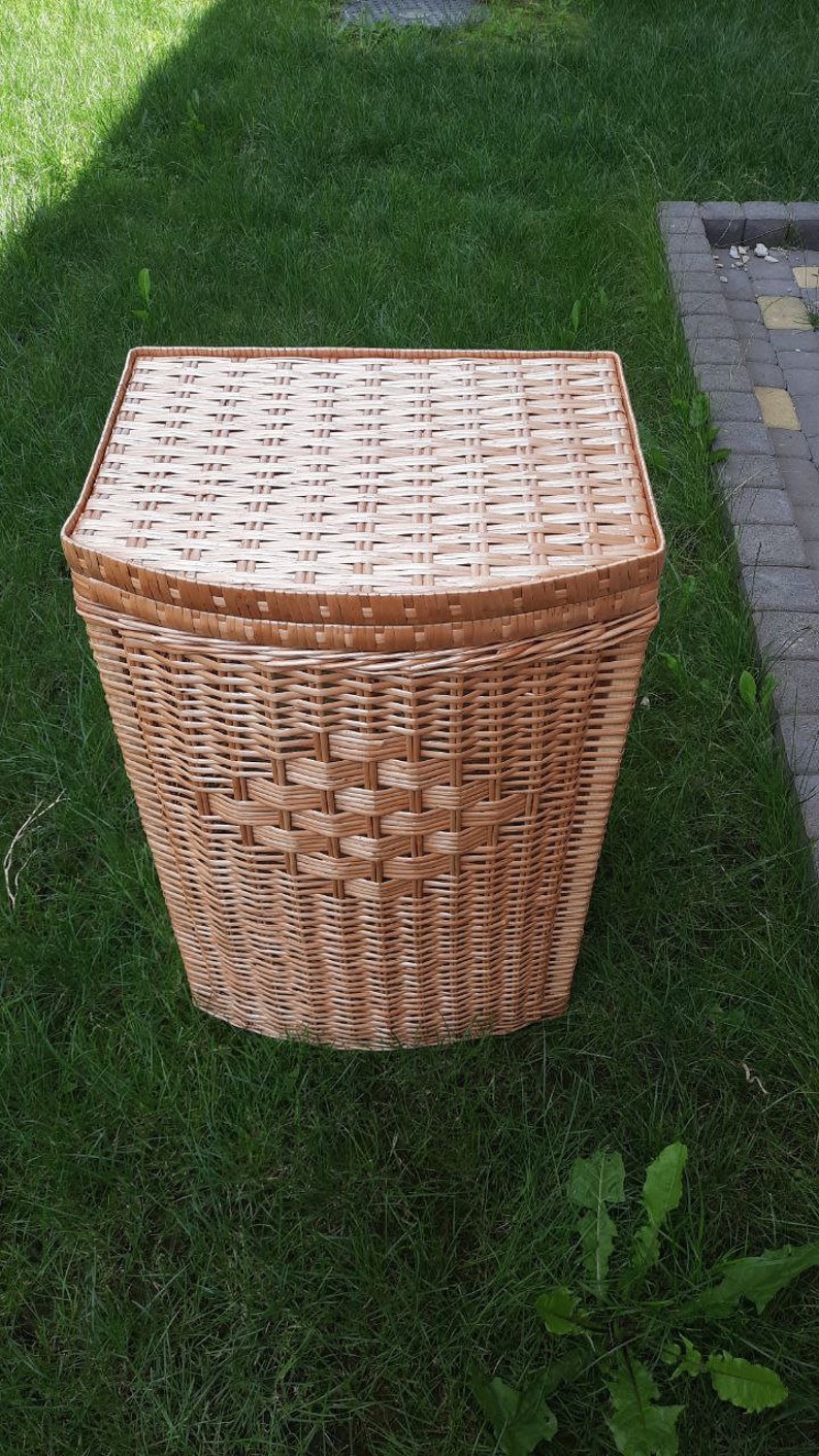 May include: A woven wicker laundry basket with a lid. The basket is light brown and has a rectangular shape.