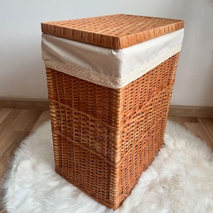 May include: A brown wicker laundry basket with a lid and a white fabric liner. The liner has a lace trim.