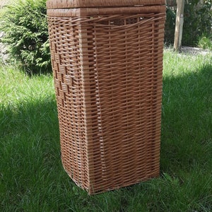 May include: A brown wicker storage basket with a rectangular shape. The basket is made of woven wicker and has a natural finish.