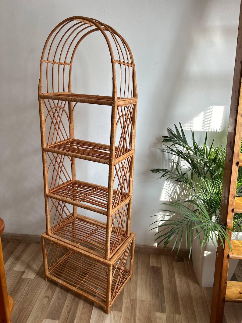 May include: A tall, arched, woven wicker shelf unit with four shelves. The shelf is made of natural brown wicker and has a rustic, bohemian style.