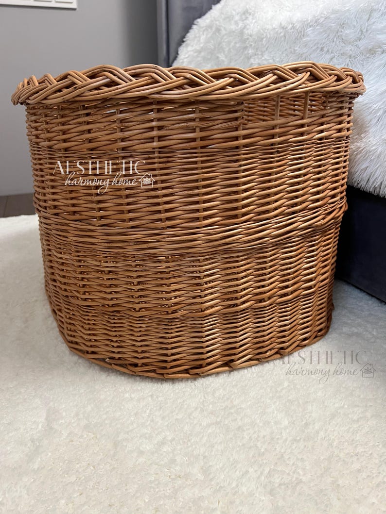 May include: A large, oval-shaped wicker basket with a woven pattern. The basket is made of natural brown wicker and has a slightly rounded bottom.